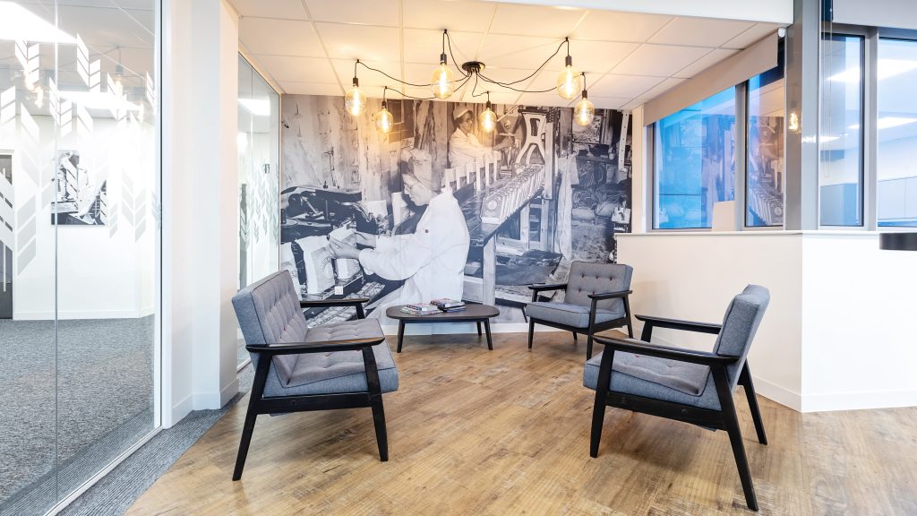 small breakout space in an office. black and white graphic of flour milling on the back wall and hanging pendant lightbulbs.