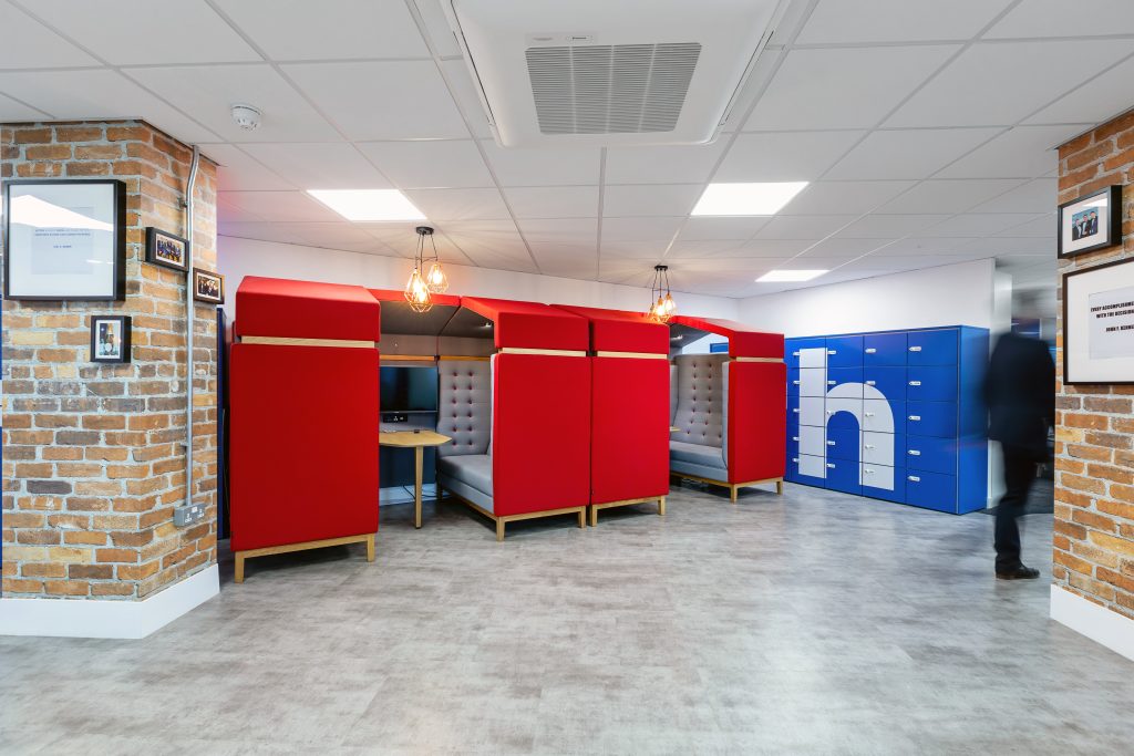 red meeting booth pods in an office, with brick columns and bright blue storage lockers.