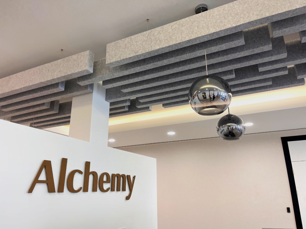 Alchemy logo on the wall with silver balls hanging from ceiling 