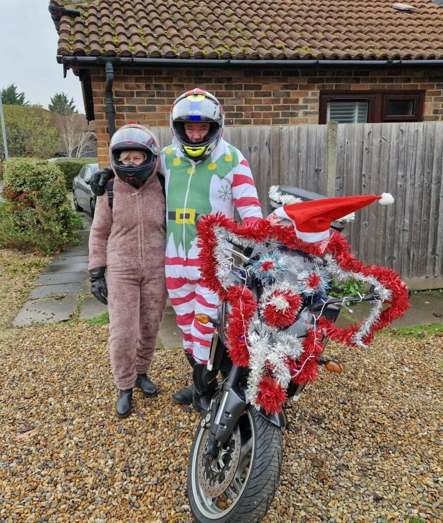 motorbike riders in Christmas attire stood next to tinsel covered motorbike