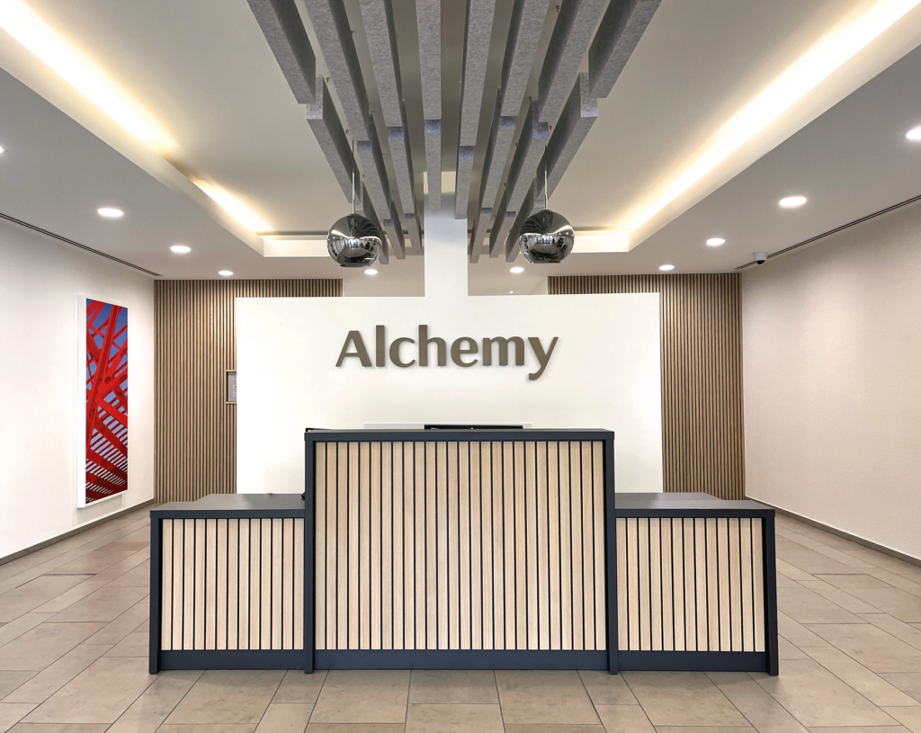 Alchemy front desk with alchemy logo on the wall