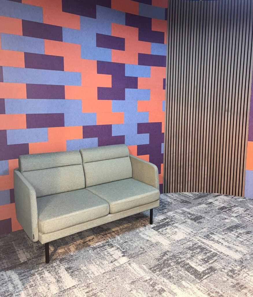 orange blue and purple brick pattern wall with two seater sofa in front