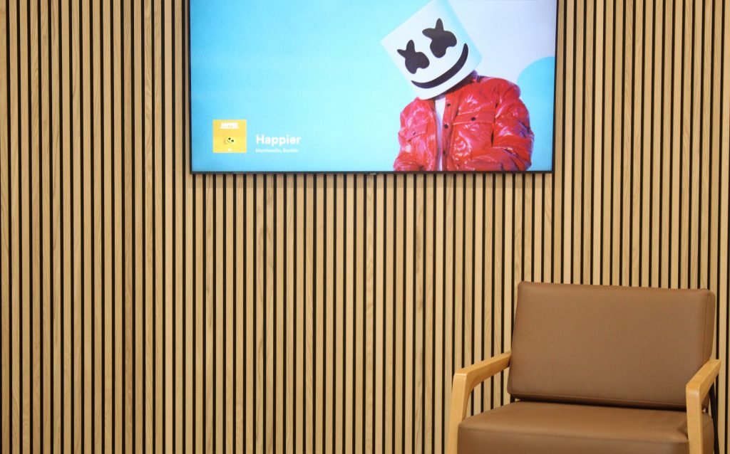beige walled waiting area with beige chair and flat screen tv
