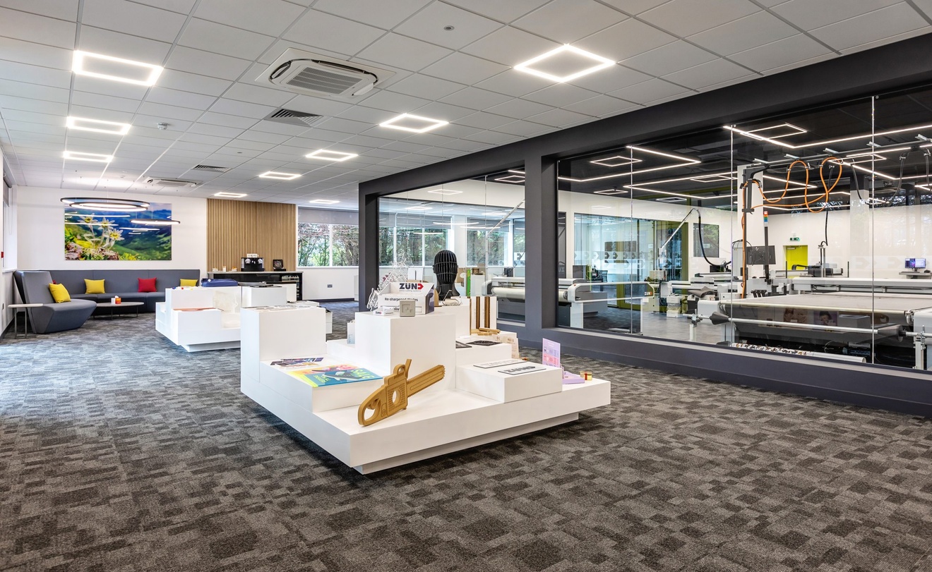 office space with machinery on the right and sculptures and product examples in the centre of the room with sofas in the background