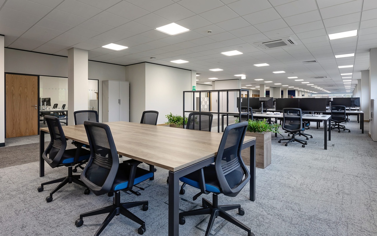 open plan office space with swivel chairs and a large meeting table with planter boxes separating desk space