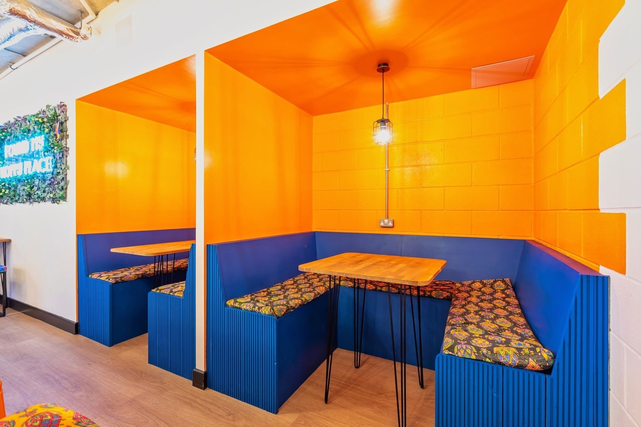 Two private working booths with blue benches, a table in the middle and orange-painted walls.