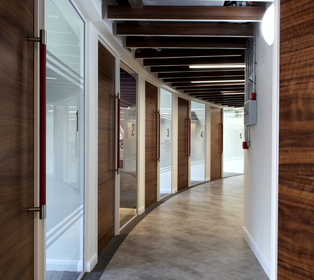 A curved hallway with five meeting/conference rooms.