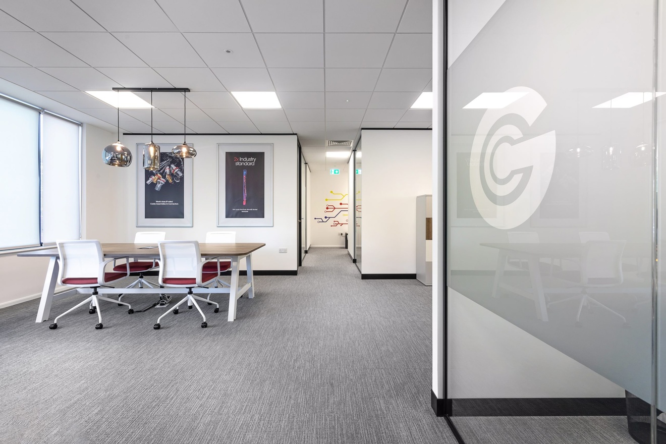 white open plan office with white and red chairs and branded posters