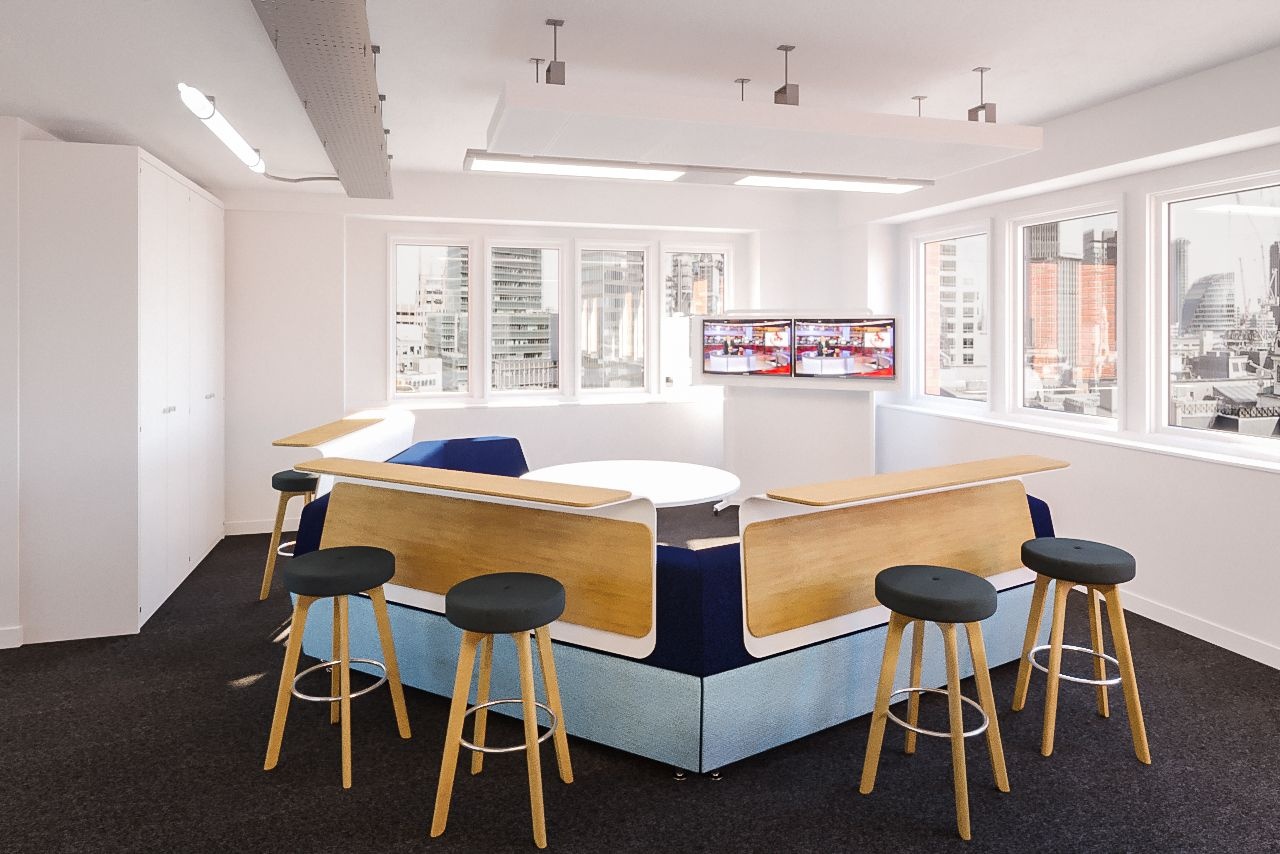 A seating area with a curved sofa that gas desks and stools around the outside of it.