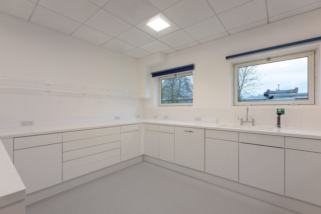 completely white kitchen area with two small windows and minimalist cupboards