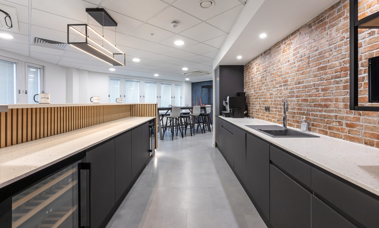 minimalist kitchen with exposed red brick wall and white counter tops with black drawers and cupboards