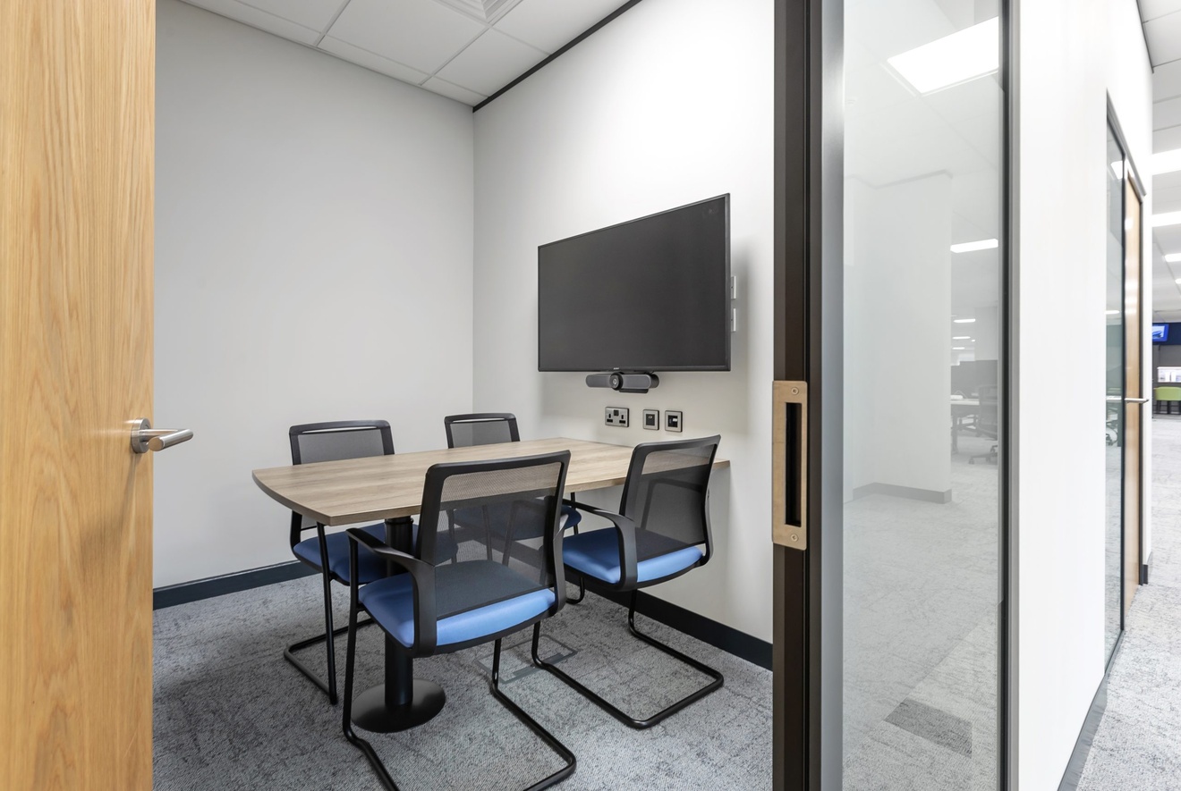 small meeting room with flat screen tv and four blue chairs
