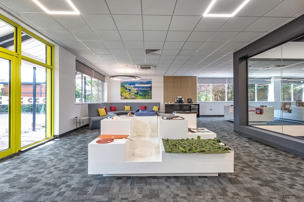 office waiting area with example products on display in the centre with a grey sofa in the background and machinery to the right