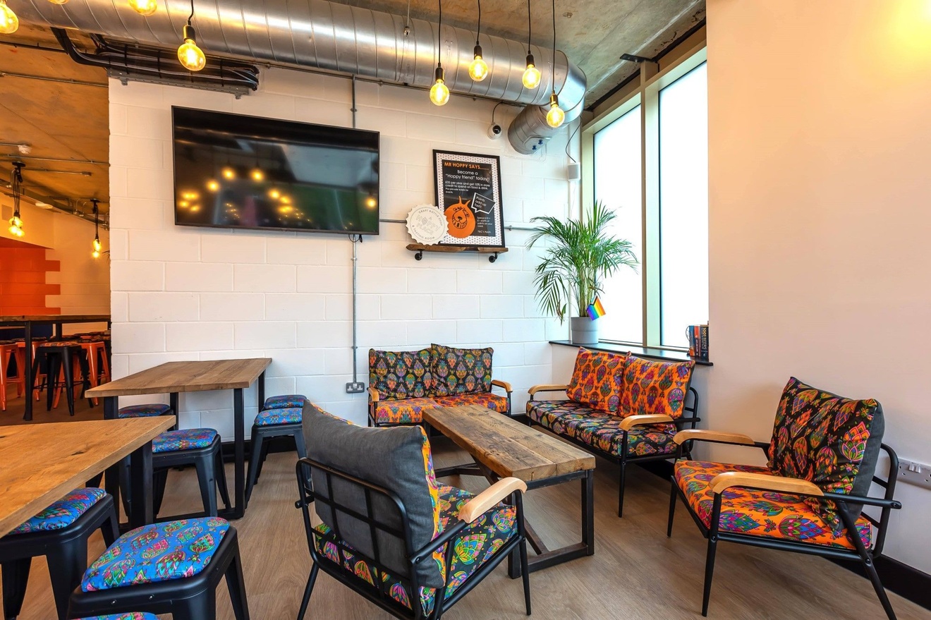 Two small sofas and two small armchairs places around a table with decorative cushions on them.