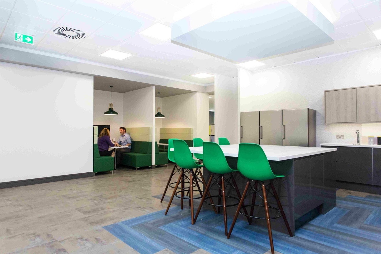 An office kitchen space with collaboration booths in the background.