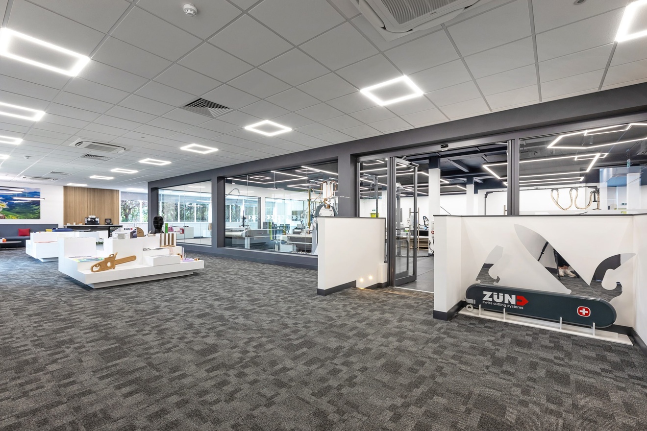 office space displaying example products with an enclosed area filled with machinery behind glass walls