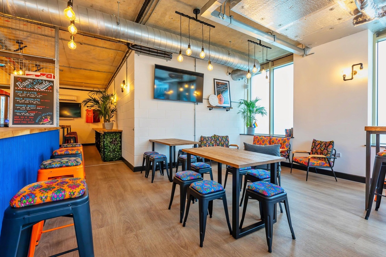 An empty bar with different assortments of seating areas, including stools, tables and chairs and arm chairs.