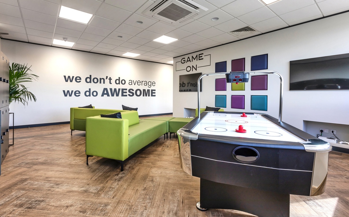communal break room with green sofas an ice hockey table and tv