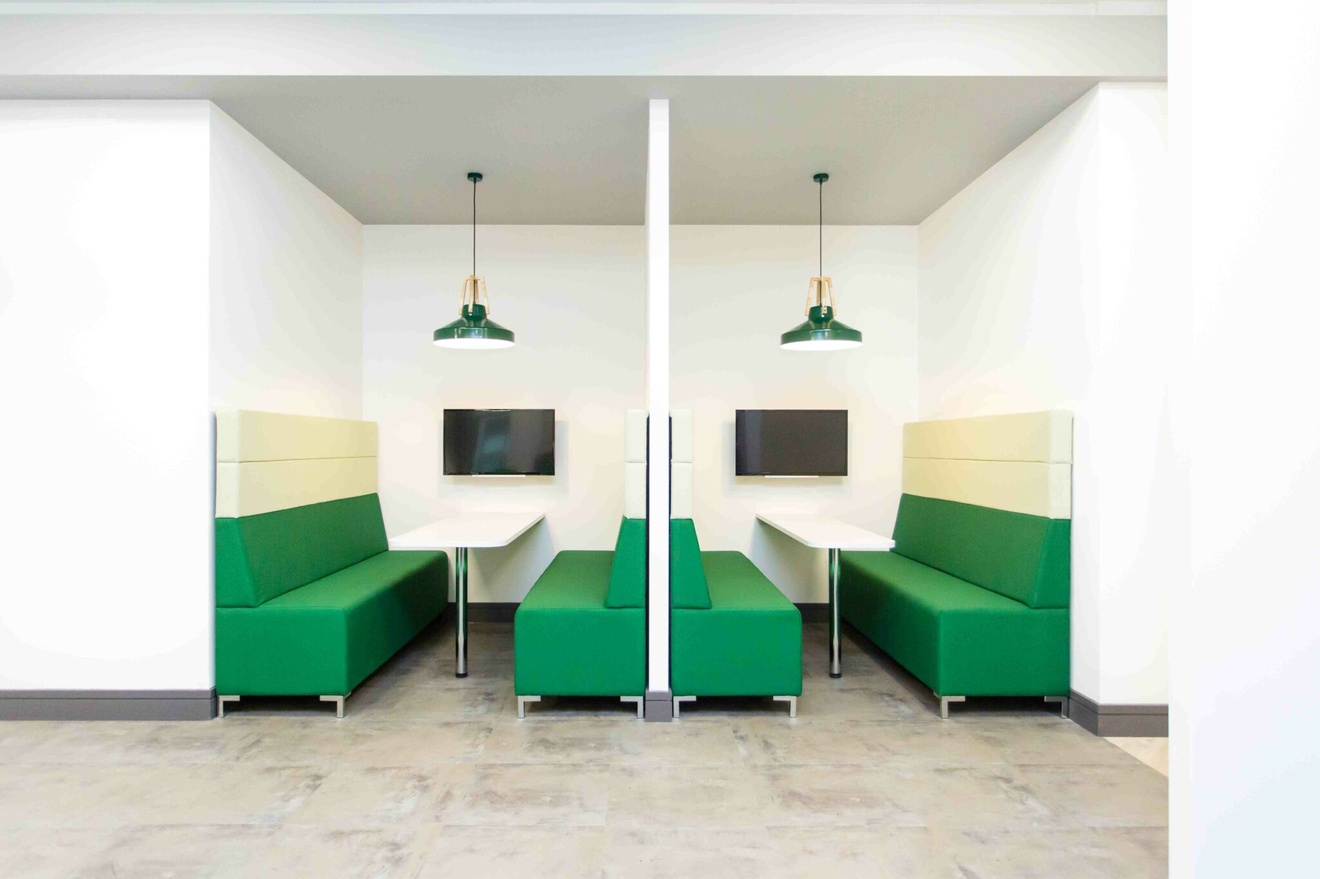 Two back to back collaboration booths with sofas, tables and televisions.