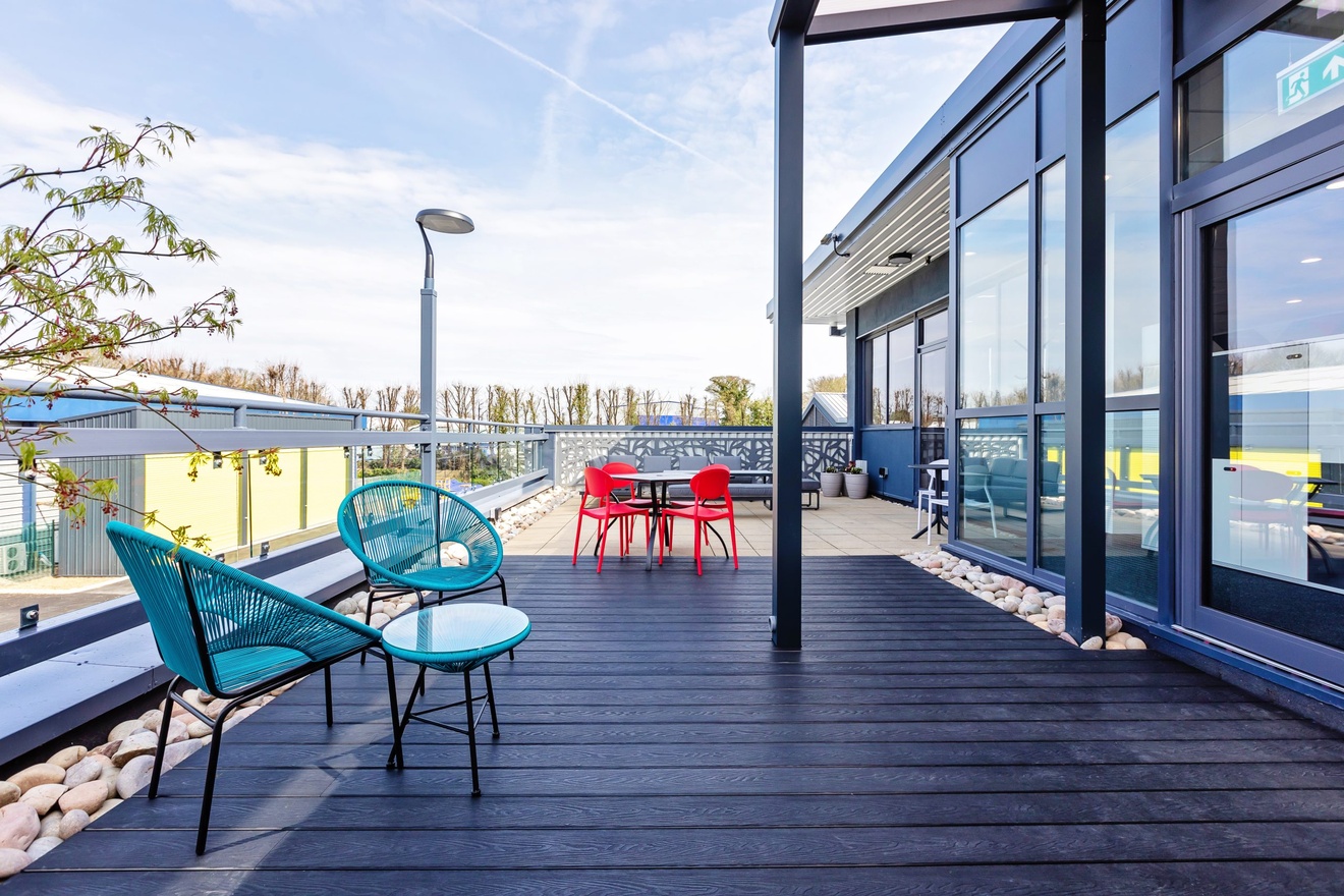 office patio with blue and red chairs and tables with cloudy blue sky and light fixtures