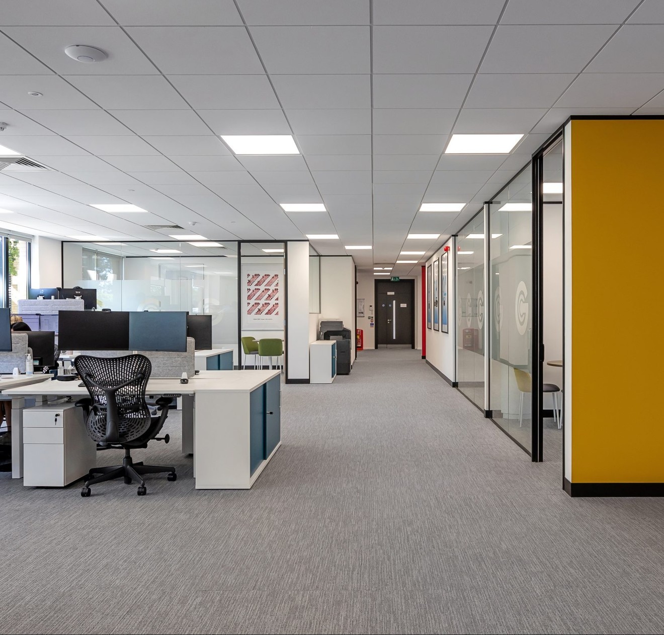 modern open office space with glass walls and white desks