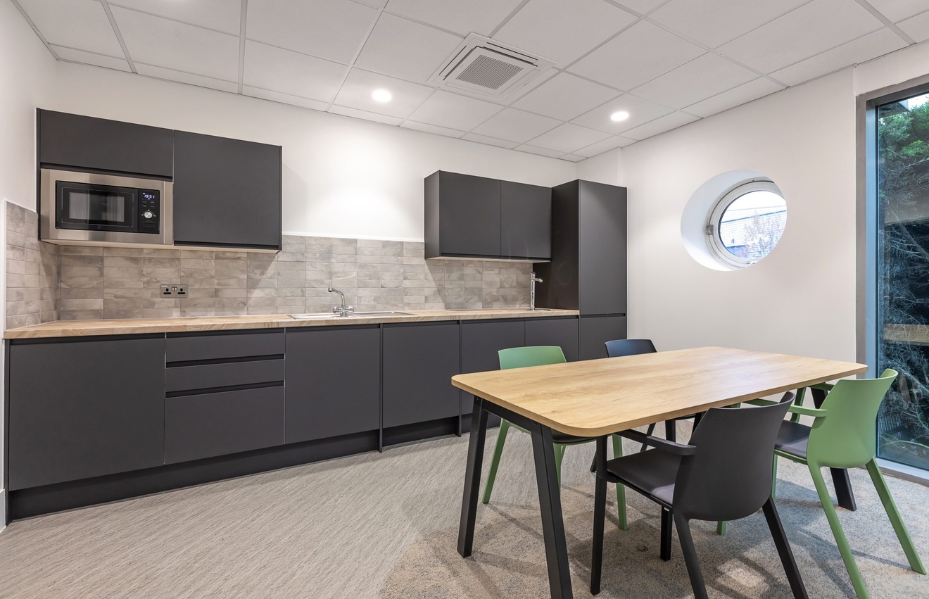 black and white minimalist kitchen with dining table with black and green chairs