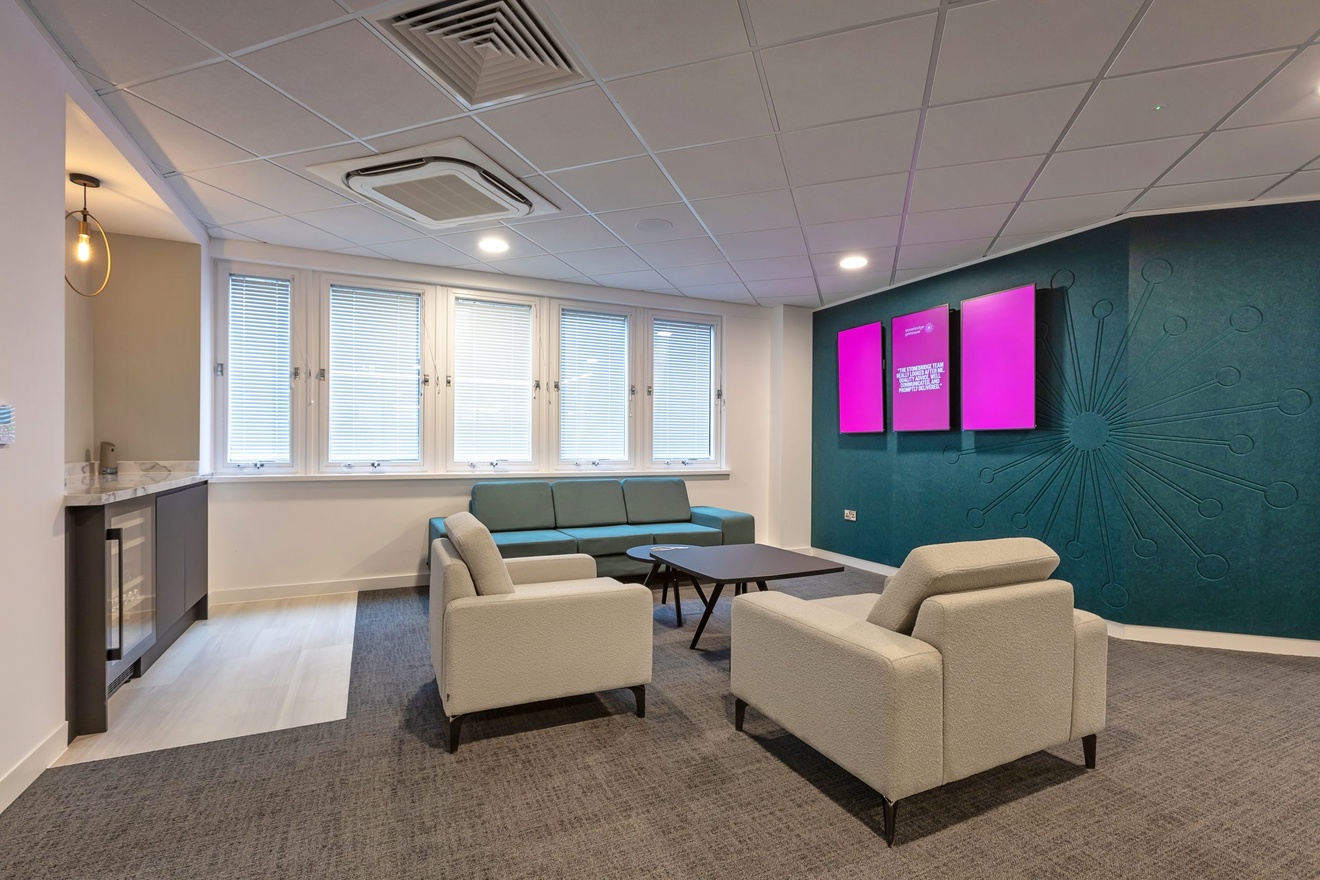 dining and waiting area with white chairs and blue sofa with pink signs on the wall
