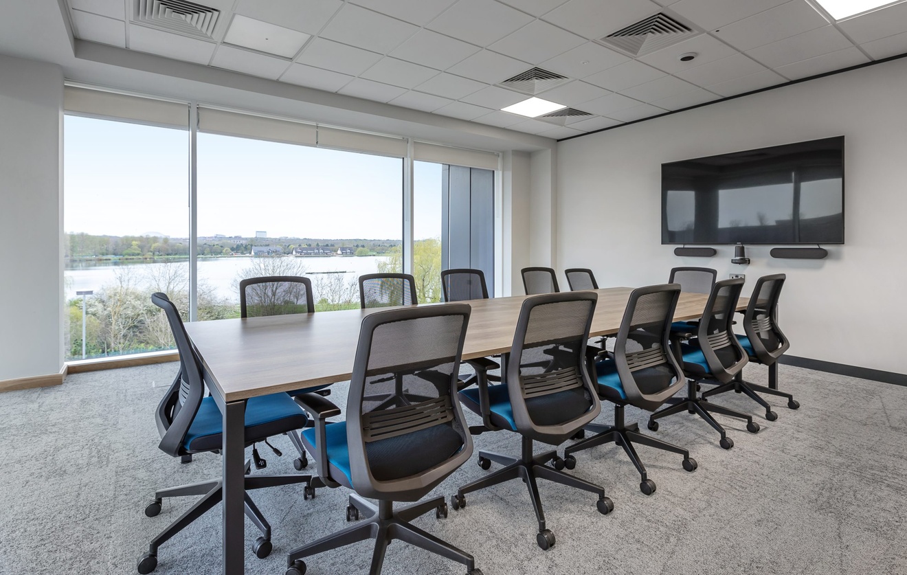 large office meeting room with flat screen tv and blue swivel chairs with large glass windows