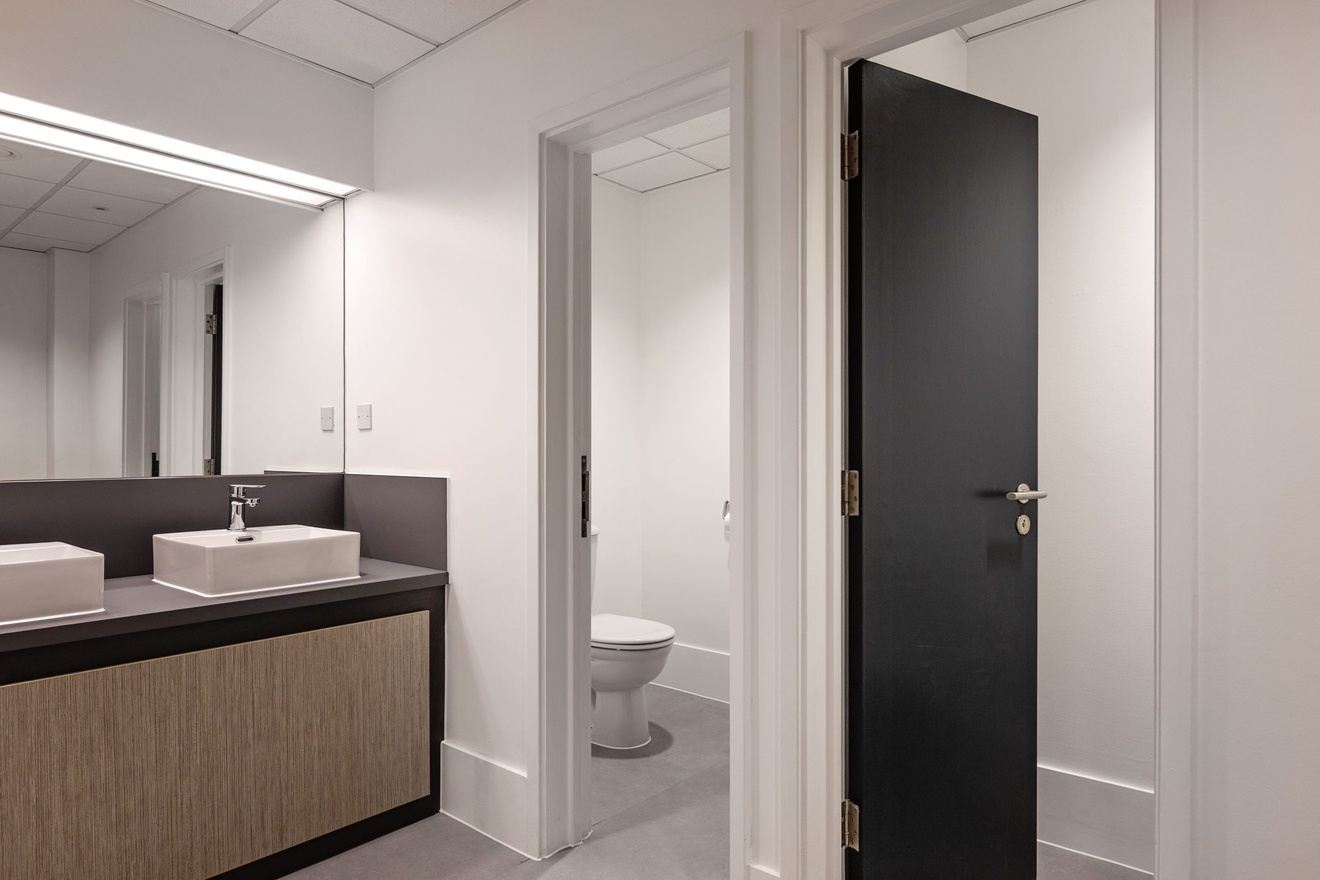 white bathroom with minimalist sink and toilet with black doors