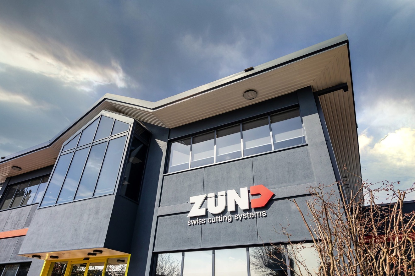 ZUND swiss cutting systems front entrance with cloudy sky above and yellow entranc edoors