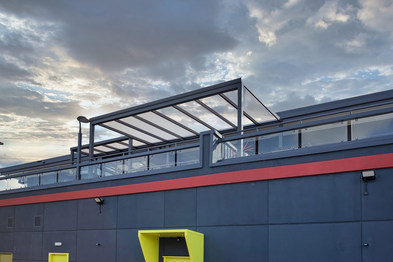 second floor balcony patio area with glass roofing and glass railing