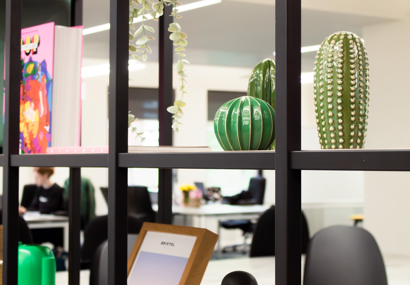 A shelving unit with glass cactus sculptures and picture frames.