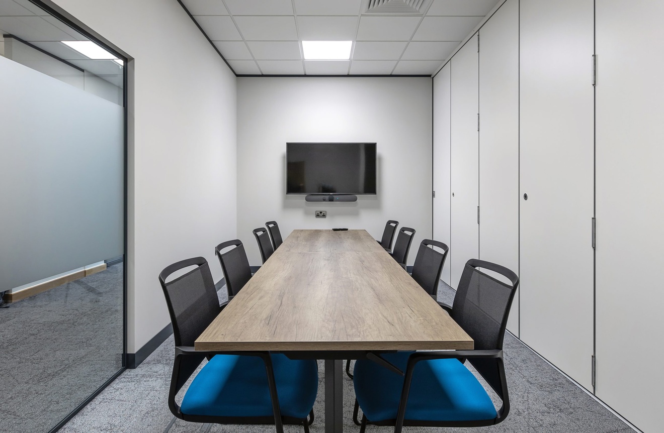 office meeting room with rectangular table flat screen tv and blue chairs