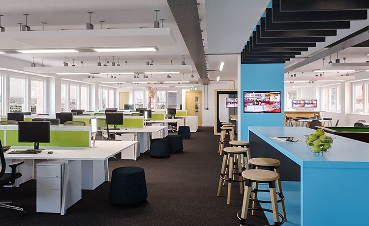 An empty office with rows of desks and a breakout area on the right.