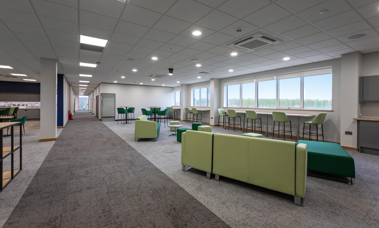 office lounge area with light green and dark green sofas and chairs