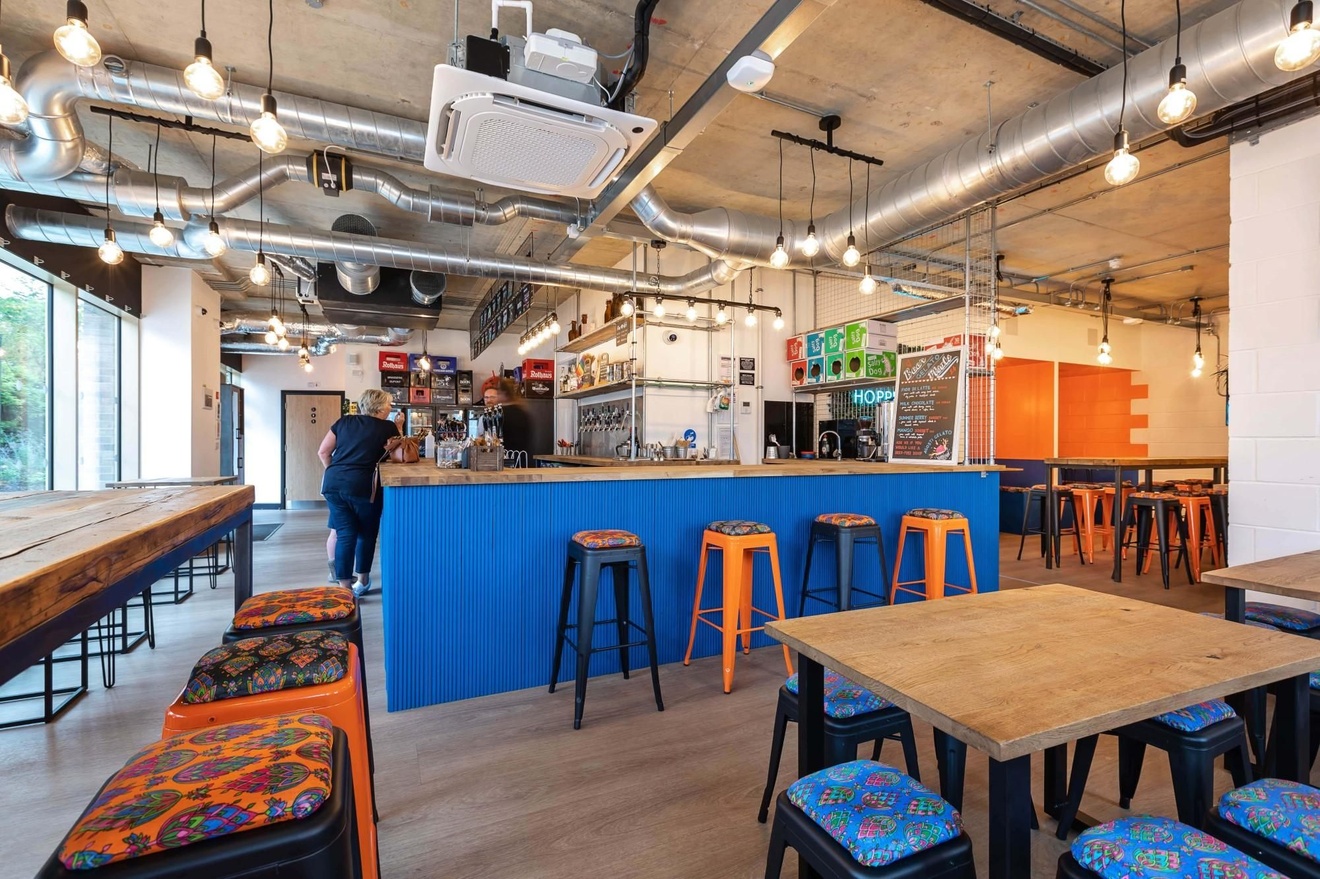 A bar with stools around it and multiple tables and chairs around the property.