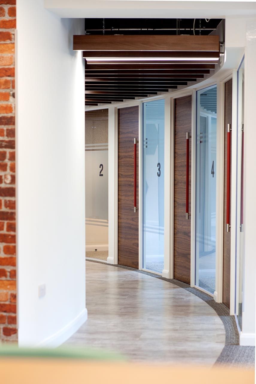 A curved hallway with four separate meeting rooms.