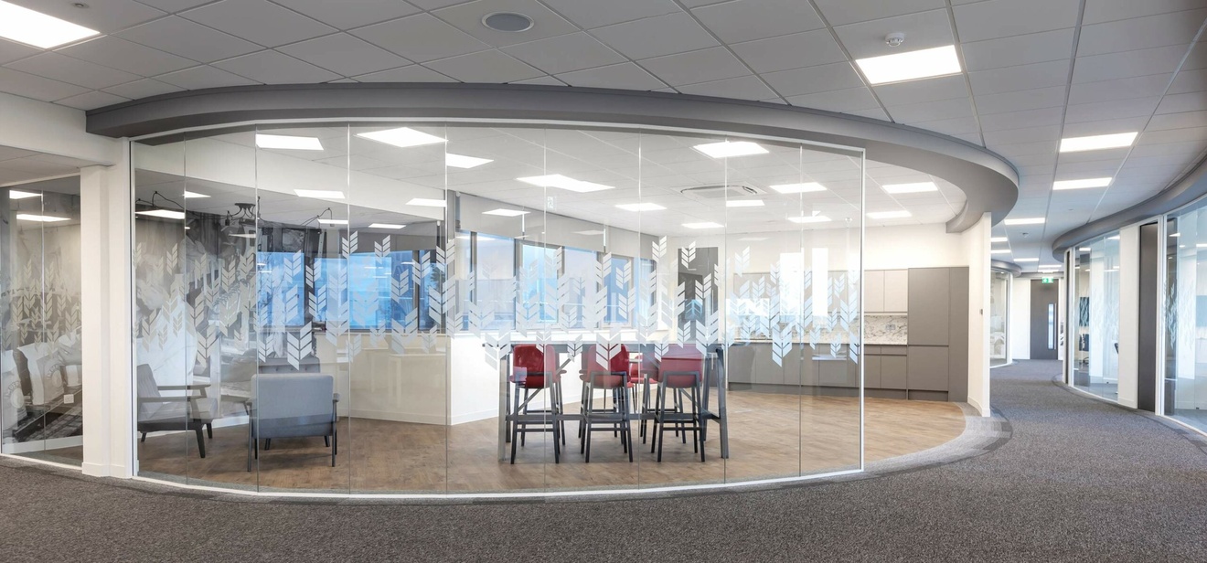 A oval-shaped breakout area in the middle of an office, separate by glass panes.