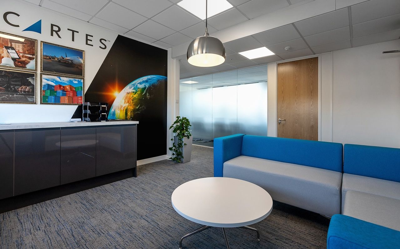 A reception area with a grey and blue sofa, coffee table and a printed-design feature wall.