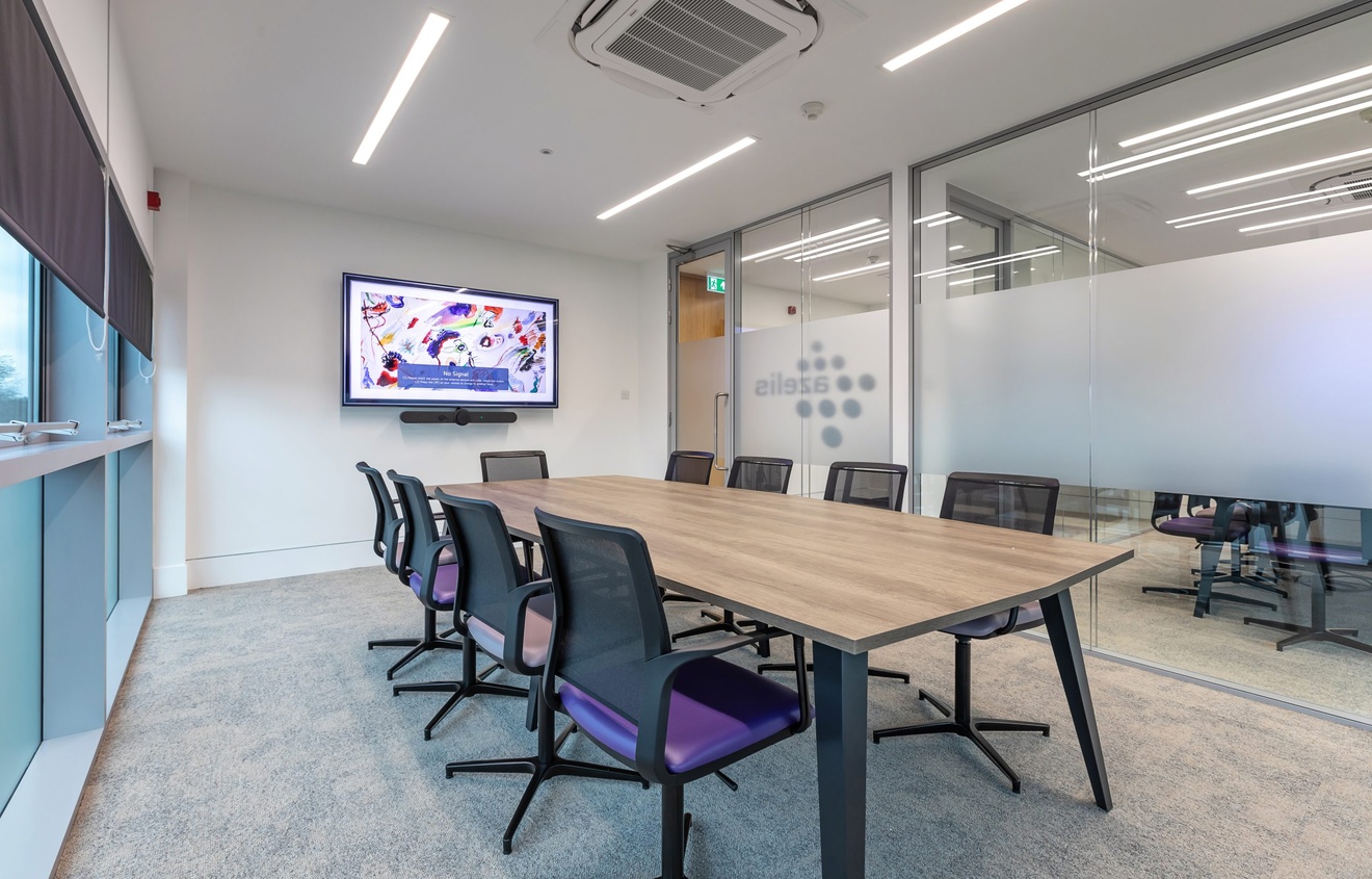 large meeting room with 9 purple and black swivel chairs with a tv mounted on the far wall