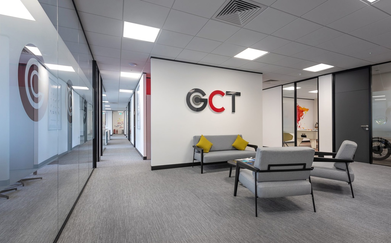 GCT sitting area with grey sofas and glass walls with GCT logo on the wall