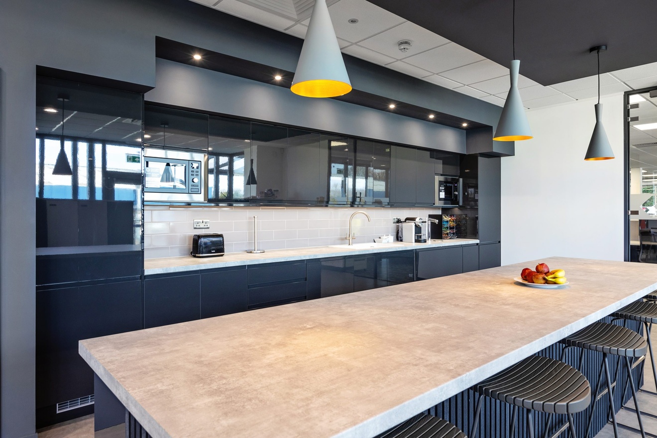 modern grey and white kitchen with barstools and hanging lights with a fruit bowl on the counter