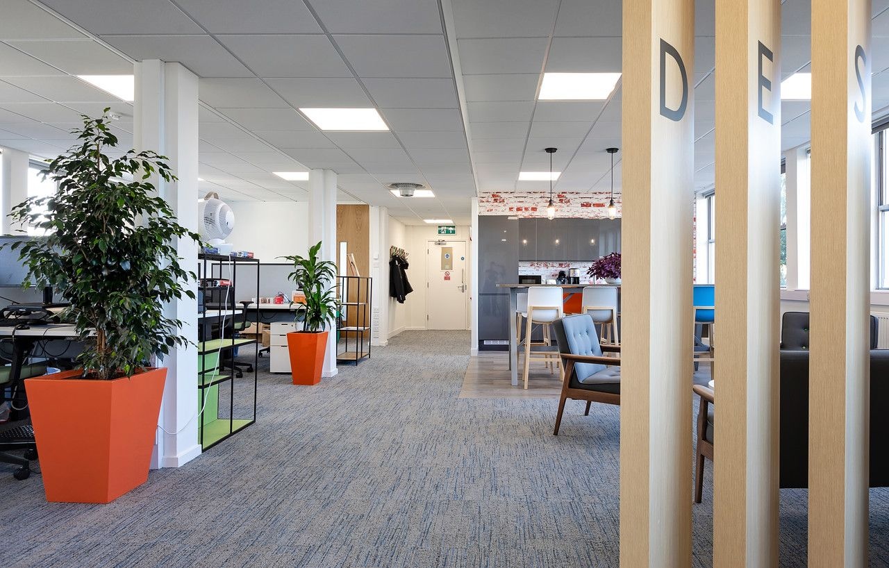 Office desks and chairs on the left and a kitchenette on the back right.