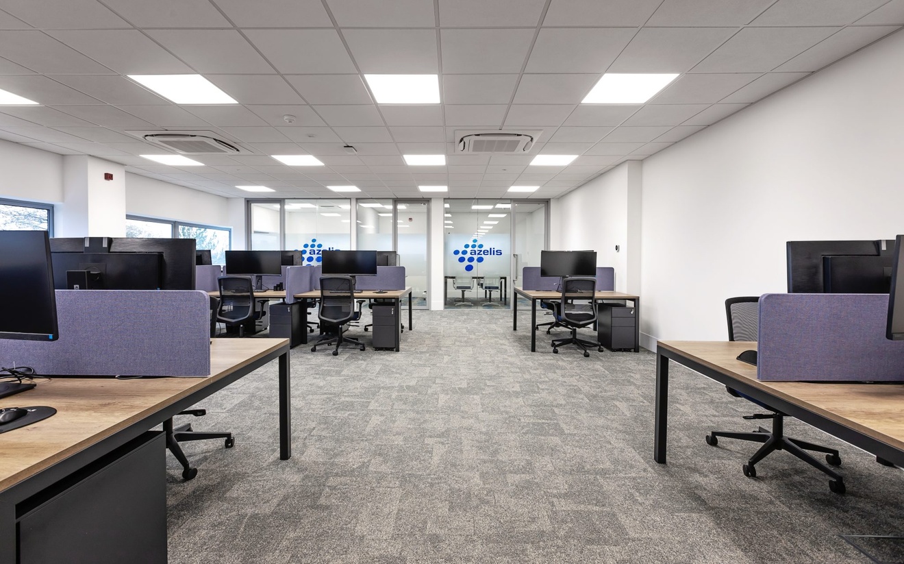 open plan office with purple dividers between desk sides with compute screens and azelis logo in the background