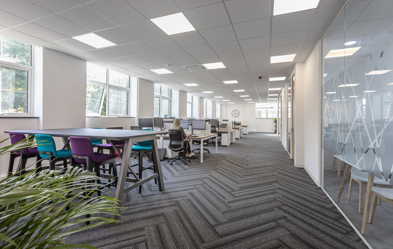 open plan office with meeting rooms to the right and pc desks to the left