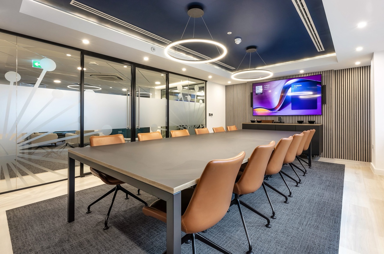 large meeting room with a large mounted tv, brown chairs and large glass double doors