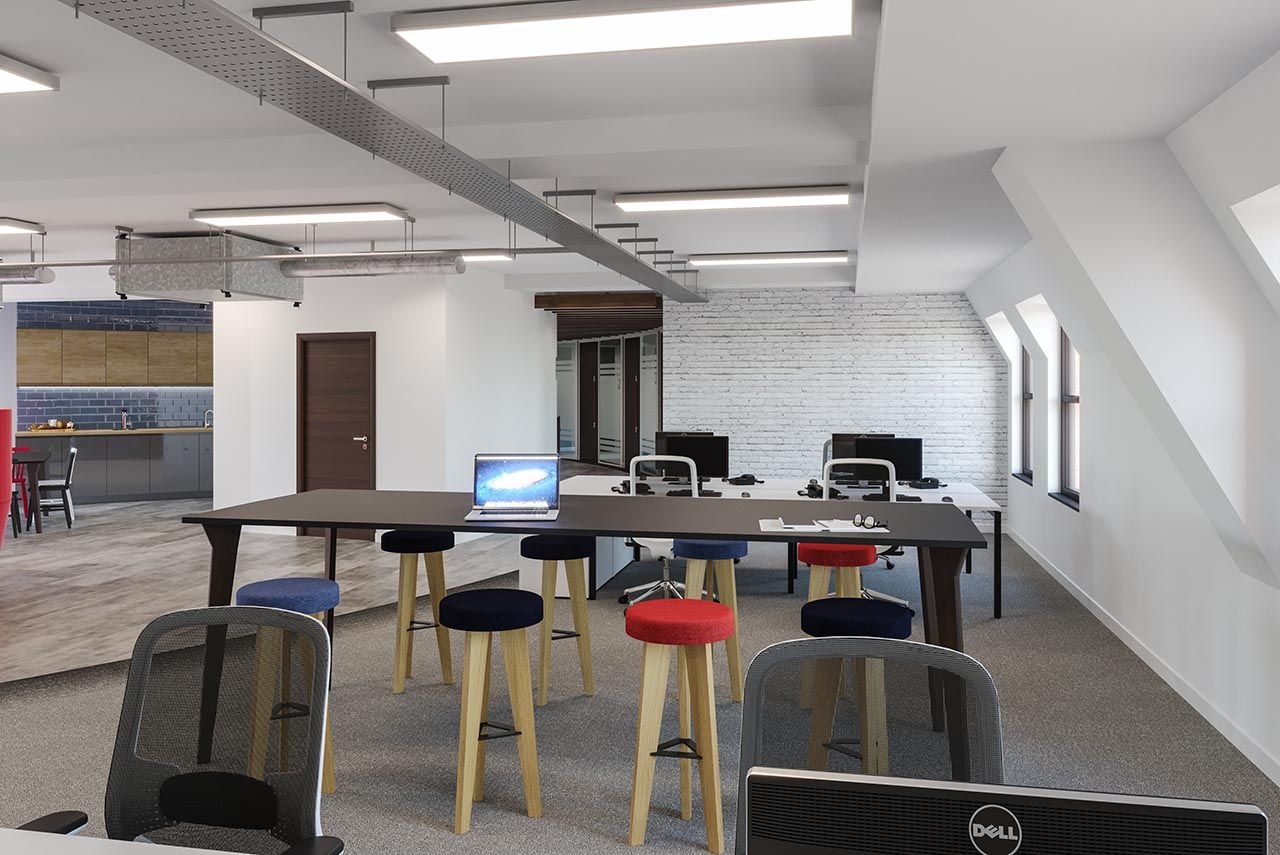 two office desks with computers and chairs, separated by a tall table with stools.
