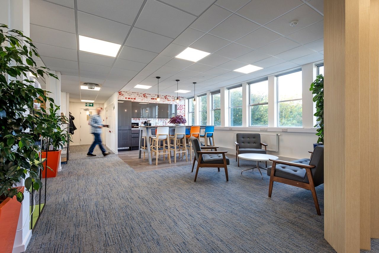 A man walking towards a kitchen space with multiple seating options.