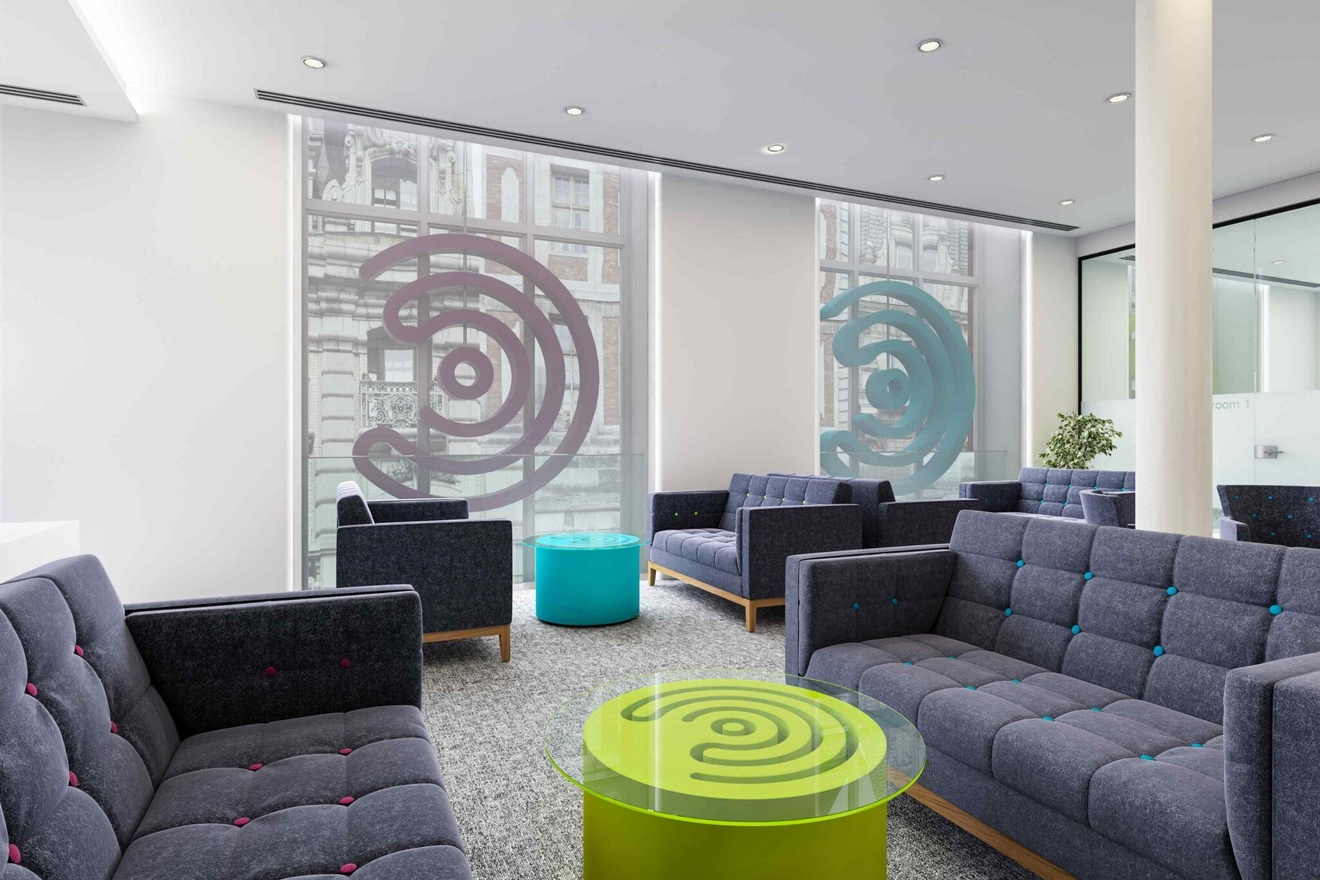 A private space with 6 grey sofas, facing each other two at a time, separated by coffee tables.