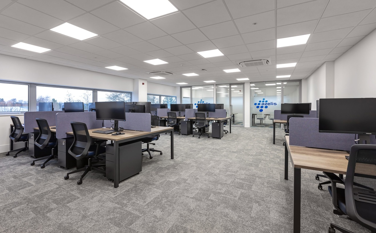 open plan modern office with black swivel chairs, computes and purple desk dividers with azelis logo in the background
